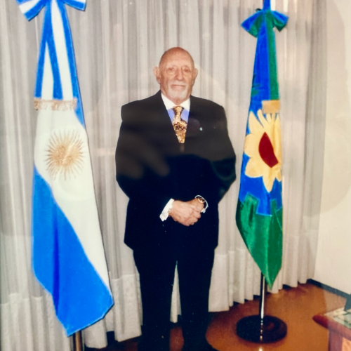 foto del fundador del estudio con la bandera argetina y la bonaerense a sus costados,seccion Historia del Estudio Jurídico Ferrari San Antonio de Padua